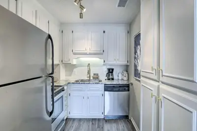 a white kitchen with white cabinets and a refrigerator at Cozy Beach Condo in Panama City Beach
