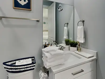 a white bathroom with a sink and a mirror at The Blue Pearls in Panama City Beach