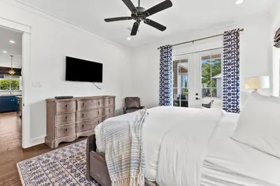 a white bedroom with a bed and a flat screen tv at 30Yay! by 30A Escapes in Watersound Beach