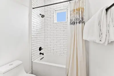 a white bathroom with a shower curtain and a toilet at 30Yay! by 30A Escapes in Watersound Beach