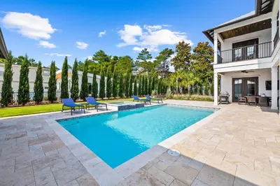 a swimming pool with blue chairs next to a house at 30Yay! by 30A Escapes in Watersound Beach