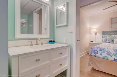 a bathroom with a sink and a mirror and a bed at Sunbird Resort Ground Floor Gem with Ocean Views! Free Beach Chairs and Umbrella! by Dolce Vita Getaways PCB in Panama City Beach