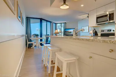 a kitchen with a bar with stools and a table at Sunbird Resort Ground Floor Gem with Ocean Views! Free Beach Chairs and Umbrella! by Dolce Vita Getaways PCB in Panama City Beach