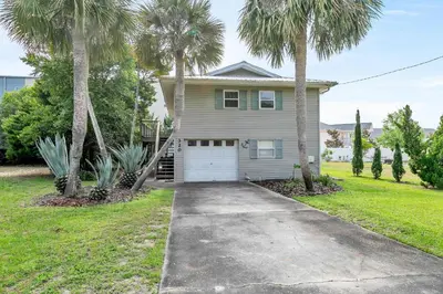 a house with palm trees in front of a driveway at Beach Haven by Emerald Coast Retreats in Panama City Beach