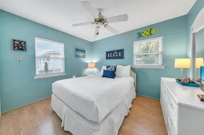 a blue bedroom with a bed and a ceiling fan at Beach Haven by Emerald Coast Retreats in Panama City Beach