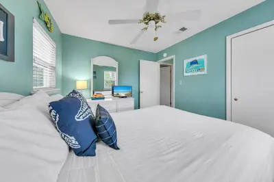a bedroom with a white bed with blue walls at Beach Haven by Emerald Coast Retreats in Panama City Beach