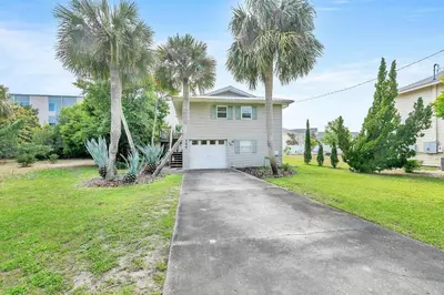 a house with palm trees in front of a driveway at Beach Haven by Emerald Coast Retreats in Panama City Beach