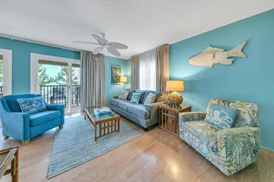 a living room with blue walls and a couch and chairs at Beach Haven by Emerald Coast Retreats in Panama City Beach