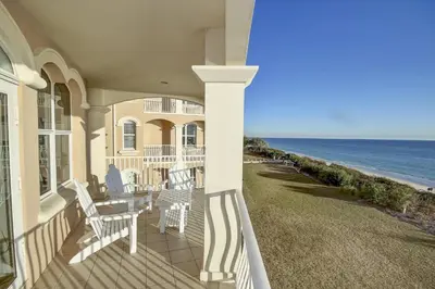 a porch of a house with white chairs and the ocean at Monterey C-201 in Seacrest