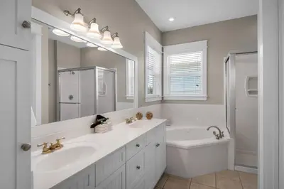 a white bathroom with a sink and a tub and a mirror at Wine Down 30A in Seacrest