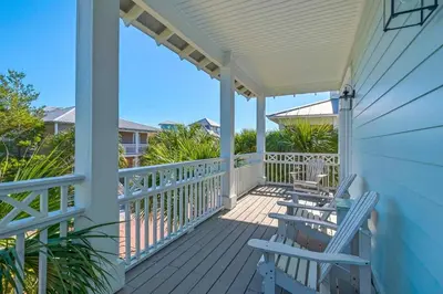 a porch with two blue chairs on it at Wine Down 30A in Seacrest