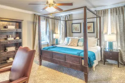 a bedroom with a canopy bed and a chair at Here & Now in Inlet Beach