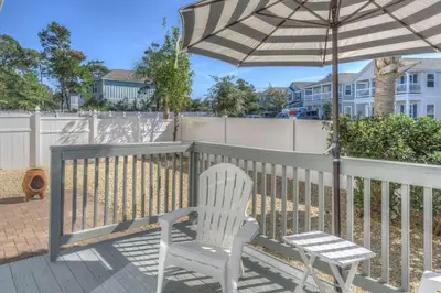 a white chair and an umbrella on a deck at Here & Now in Inlet Beach