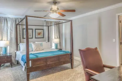 a bedroom with a canopy bed with a ceiling fan at Here & Now in Inlet Beach