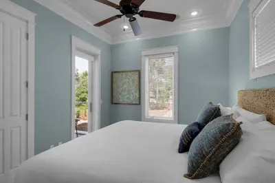 a bedroom with a bed with blue walls and a ceiling fan at Scout's Lookout in Inlet Beach