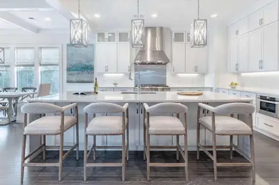 a kitchen with white cabinets and a large island with bar stools at Paradise Found 30A in Seacrest