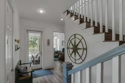 a hallway with a staircase with a large clock on the wall at The Yellow Rose in Santa Rosa Beach
