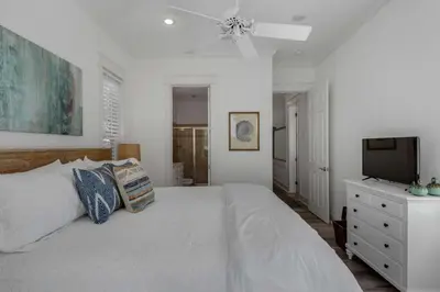 a white bedroom with a bed and a television at The Yellow Rose in Santa Rosa Beach