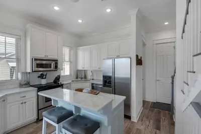a kitchen with white cabinets and a stainless steel refrigerator at The Yellow Rose in Santa Rosa Beach