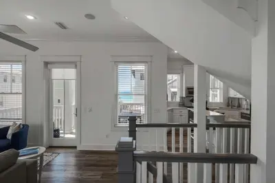 a living room with white walls and a staircase at The Yellow Rose in Santa Rosa Beach