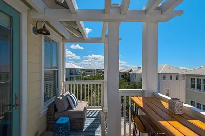 a pergola on a porch with a bench at The Yellow Rose in Santa Rosa Beach