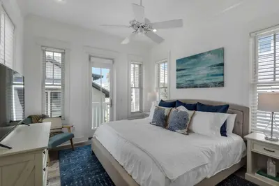 a bedroom with a bed and a desk and windows at The Yellow Rose in Santa Rosa Beach