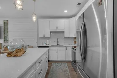 a kitchen with white cabinets and a refrigerator at Feeling Tip Sea in Santa Rosa Beach