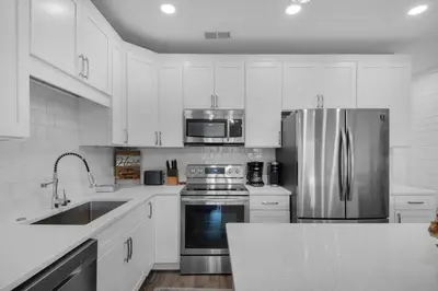 a kitchen with white cabinets and a stainless steel refrigerator at Feeling Tip Sea in Santa Rosa Beach