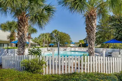 a white fence with two palm trees and a pool at Beachwood Villas 7G in Santa Rosa Beach