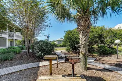a park with a bench and a palm tree at Beachwood Villas 7G in Santa Rosa Beach