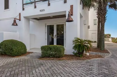 a white building with palm trees in front of it at The Penthouse at Seagrove in Santa Rosa Beach