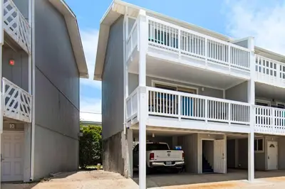 a building with white balconies and a truck parked in a parking lot at Cloud Nine By the Sea in Inlet Beach