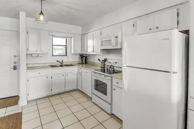 a kitchen with white cabinets and a white refrigerator at Beachside 10 in Santa Rosa Beach