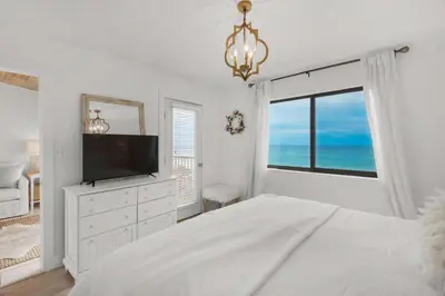 a white bedroom with a tv and a large window at Beachside 10 in Santa Rosa Beach