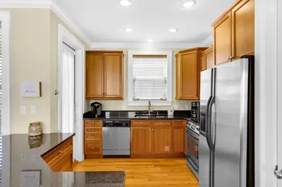 a kitchen with wooden cabinets and a stainless steel refrigerator at Palms and Pines in Rosemary Beach