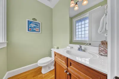 a bathroom with a sink and a toilet and a window at Palms and Pines in Rosemary Beach