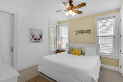 a bedroom with a white bed and a ceiling fan at Palms and Pines in Rosemary Beach