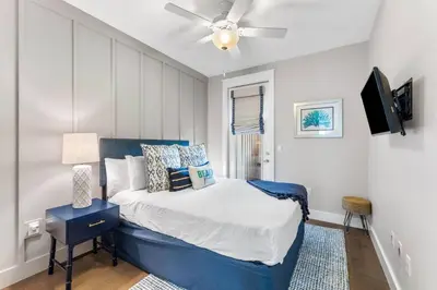 a bedroom with a blue bed with a ceiling fan at Saltwater Sanctuary in Santa Rosa Beach
