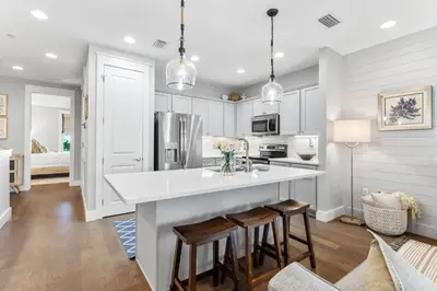 a kitchen with white cabinets and a large island with stools at Saltwater Sanctuary in Santa Rosa Beach
