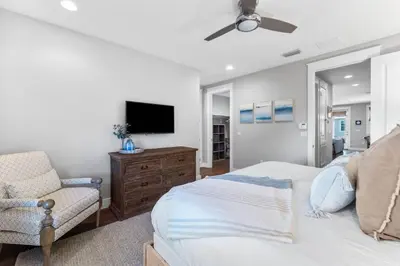 a bedroom with a bed and a tv and a chair at Saltwater Sanctuary in Santa Rosa Beach