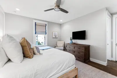 a bedroom with a bed with a television and a chair at Saltwater Sanctuary in Santa Rosa Beach