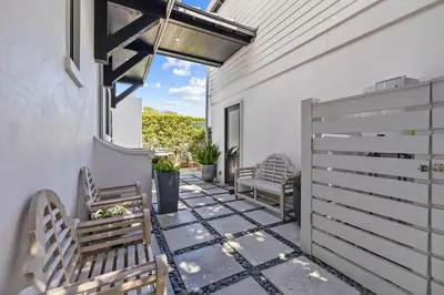 a patio with two benches and a fence at Abba Cottage in Rosemary Beach
