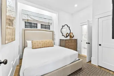 a white bedroom with a bed and a window at Abba Cottage in Rosemary Beach
