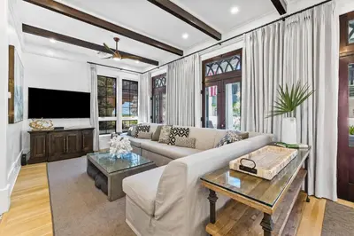 a living room with a couch and a tv at Abba Cottage & Carriage House in Rosemary Beach