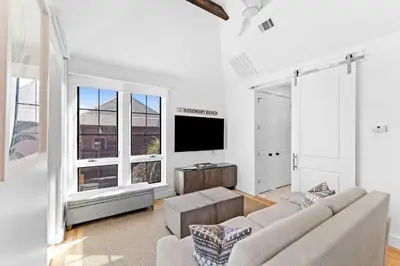 a living room with a couch and a flat screen tv at Abba Carriage House in Rosemary Beach