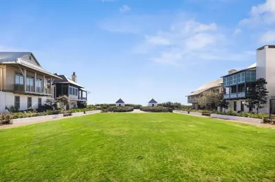 a large grassy yard with houses in the background at Abba Carriage House in Rosemary Beach