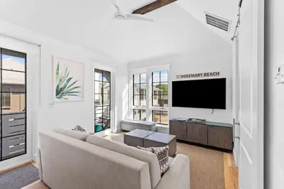 a living room with a couch and a flat screen tv at Abba Carriage House in Rosemary Beach