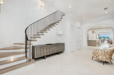 a white living room with a staircase and a chair at Devonshire West in Seacrest
