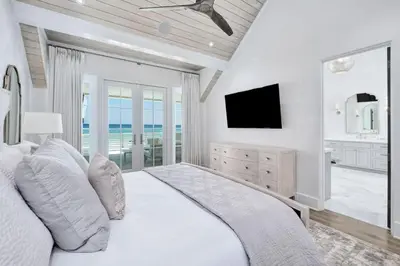 a white bedroom with a bed and a television at Devonshire West in Seacrest