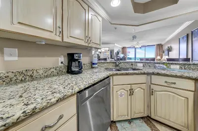 a kitchen with wooden cabinets and granite counter tops at Summerhouse 1012C in Panama City Beach